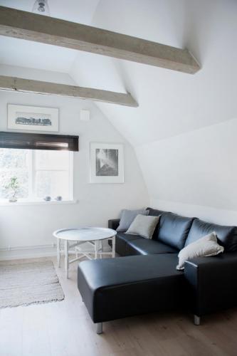 a living room with a black couch and a table at Mullbärsgårdens Bed and Breakfast in Visby