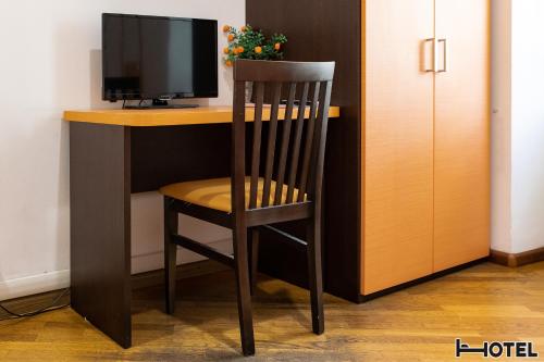 a wooden chair sitting at a desk with a television at Hotel Youri Il Magnifico in Genova
