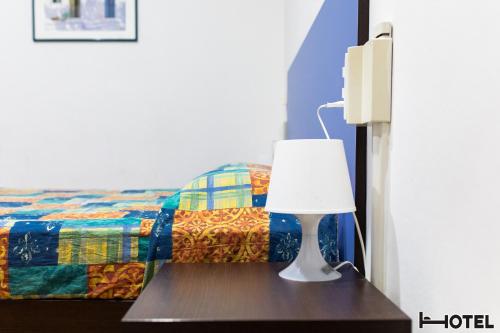 a lamp on a table next to a bed at Hotel Youri Il Magnifico in Genova