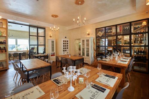 un restaurante con mesas y sillas de madera y una habitación con botellas de vino en Hiša Ančka, Boutique Hotel & Maja Rooms, en Slovenj Gradec