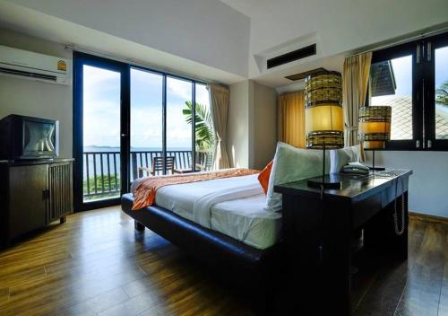 a bedroom with a bed with a view of the ocean at Merit Resort Samui in Lamai