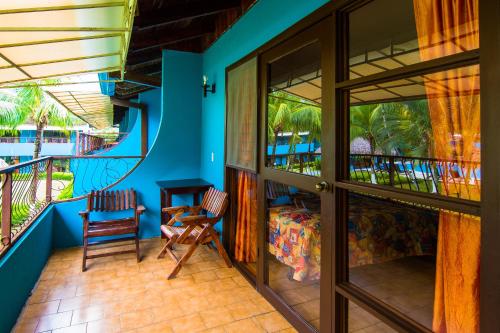 a room with a balcony with a bed and chairs at Beach Break Resort & CR Surf Camp in Jacó