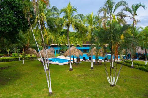 a resort with palm trees and a swimming pool at Beach Break Resort & CR Surf Camp in Jacó