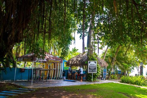 a table and chairs under a tree with a sign at Beach Break Resort & CR Surf Camp in Jacó