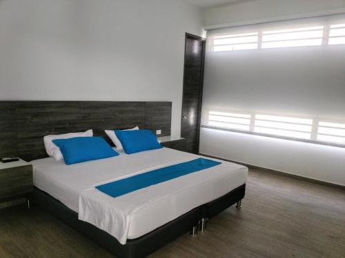 a bedroom with a large bed with blue pillows at Hostel Laguna Salá By FSL in Ríohacha