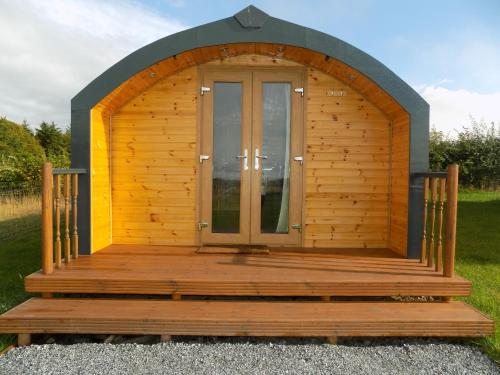 a wooden cabin with a door in the grass at Greencraig Pods in Buckie