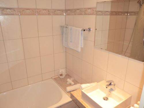 a white bathroom with a sink and a tub at Hotel Altenberg in Baden-Baden