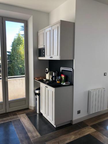 Elle comprend une petite cuisine avec des placards blancs et une fenêtre. dans l'établissement Exceptionnel, 130 m2, vue aérienne sur Paris, à Ville-dʼAvray