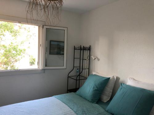 a bedroom with a bed with blue pillows and a window at **** Beau T2 de 40 m2, jardin de 70m2, au calme, à 50 mètres de la plage in Le Pradet