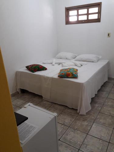 a bedroom with a bed with two pillows on it at Pousada Pelourinho in Mucuri