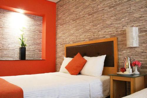 a bedroom with a bed and a brick wall at Hotel Colonial Hermosillo in Hermosillo