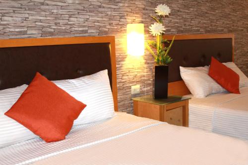 a hotel room with two beds with orange and white pillows at Hotel Colonial Hermosillo in Hermosillo