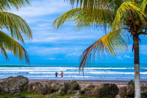 two people standing on a beach with the ocean at Beach Break Resort & CR Surf Camp in Jacó