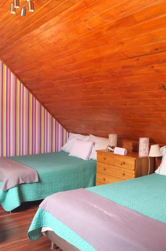 two beds in a room with a wooden ceiling at Cabañas Yukatan Lago de Tota in Tota