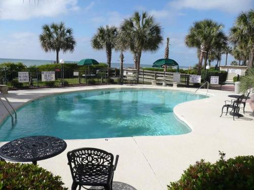 a swimming pool with chairs and tables and palm trees at The Palms Resort-Oceanfront in Myrtle Beach