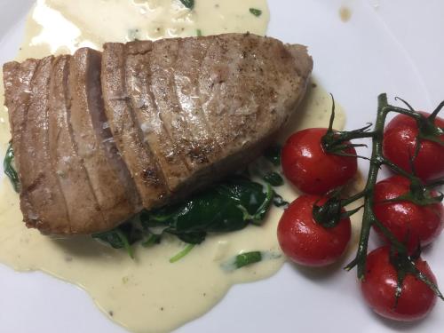 a piece of steak on a white plate with tomatoes at Hotel Hromovka in Špindlerův Mlýn
