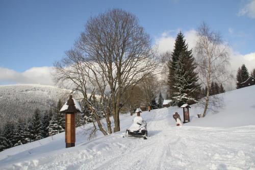 a snow covered road with a snowmobile in the snow at Hotel Hromovka in Špindlerův Mlýn