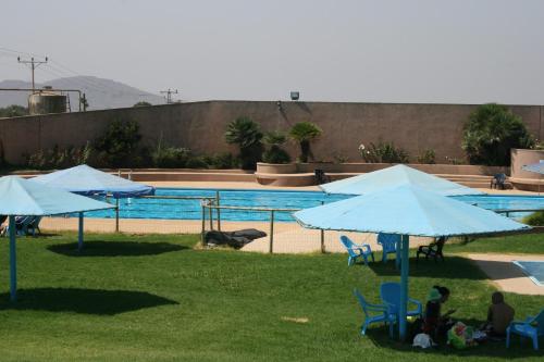 a group of people sitting under umbrellas near a swimming pool at Ein Zivan Village Resort in Ein Zivan