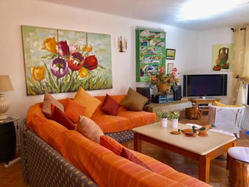 a living room with an orange couch and a table at FARMHOUSE CASA DA AVÓ in Loulé