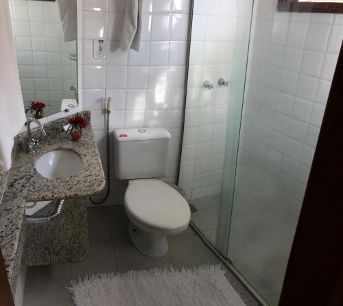 a bathroom with a toilet and a glass shower at Porto Geraes Praia Hotel in Porto Seguro