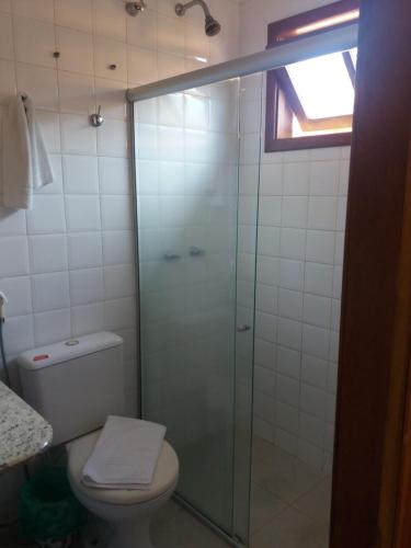 a bathroom with a toilet and a glass shower at Porto Geraes Praia Hotel in Porto Seguro