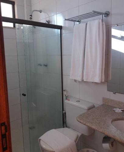 a bathroom with a shower and a toilet and a sink at Porto Geraes Praia Hotel in Porto Seguro