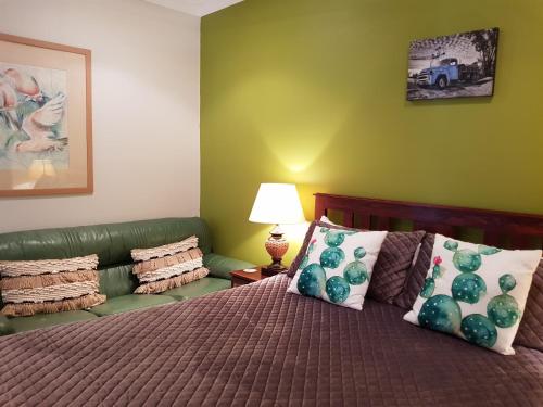 1 dormitorio con 1 cama y 1 sofá verde en Sonja's Bed and Breakfast, en Lightning Ridge