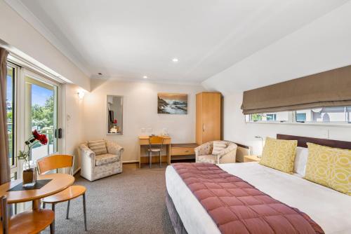 Una habitación de hotel con una cama grande y un escritorio. en Colombo In The City, en Christchurch