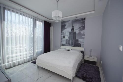sypialnia z łóżkiem i zdjęciem budynku w obiekcie Apartamenty Triston Park w Warszawie