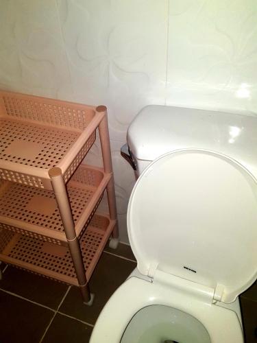 a bathroom with a toilet with a shelf next to it at MJ Room Rental in Panglao