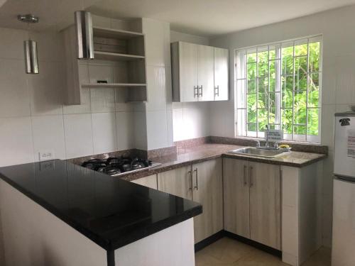 a kitchen with white cabinets and a black counter top at Apartamentos Martinez in San Andrés