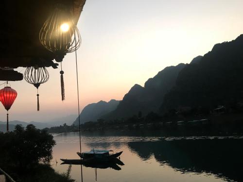 a boat on a river with mountains in the background at Phong Nha Coco House in Phong Nha