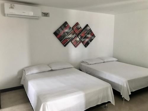 two beds in a room with white walls at Apartamentos Martinez in San Andrés