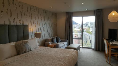 1 dormitorio con cama, sofá y TV en Bluestone On George, en Dunedin