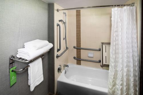 a bathroom with a tub and a sink with towels at Hyatt Place Dallas Park Central in Dallas