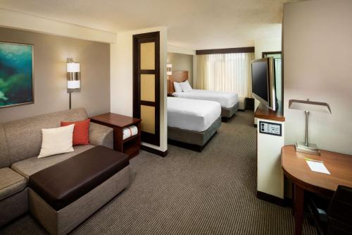 una camera d'albergo con un letto e un divano e una camera con due letti di Hyatt Place Dallas Park Central a Dallas