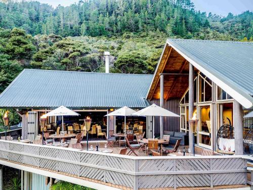 a building with tables and chairs and umbrellas at Grand Mercure Puka Park Resort in Pauanui