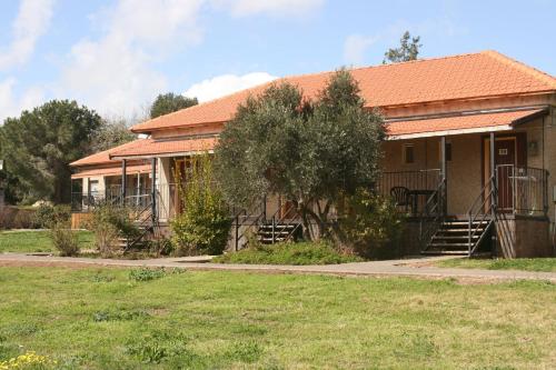 a house with an orange roof and a grass field at Ein Zivan Village Resort in Ein Zivan
