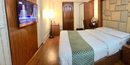a bedroom with a large bed and a tv at Star Guest House in Karachi