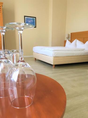 a room with a bed and a table with wine glasses at Pension Am Pollingpark in Dessau