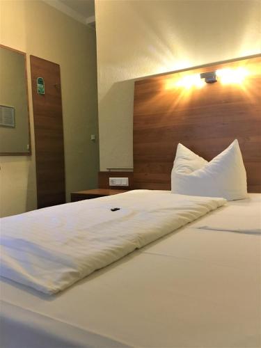 a large bed with white sheets and a wooden headboard at Pension Am Pollingpark in Dessau