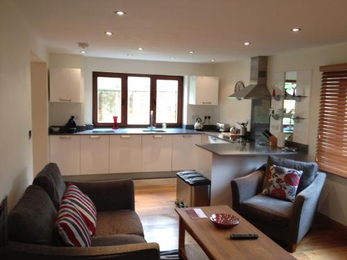 a living room with two chairs and a kitchen at Ashbrook Lets Apartments in Blewbury