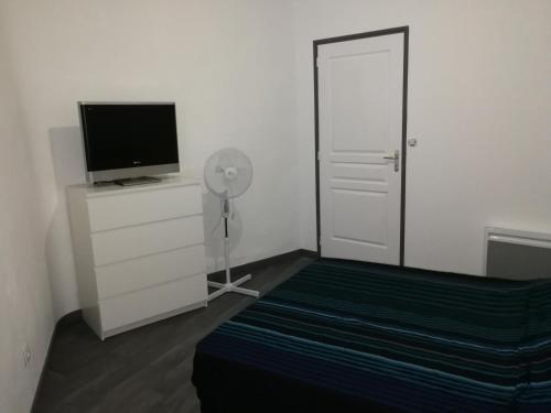 Schlafzimmer mit einem TV und einer Tür mit einem Ventilator in der Unterkunft Appartement à 500m de la plage in Mèze