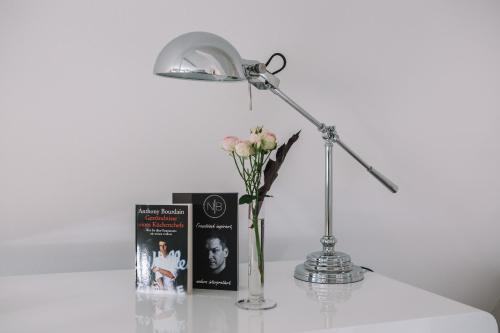 a table with a lamp and a book and a vase with flowers at Boutique Hotel Pfauen in Schorndorf
