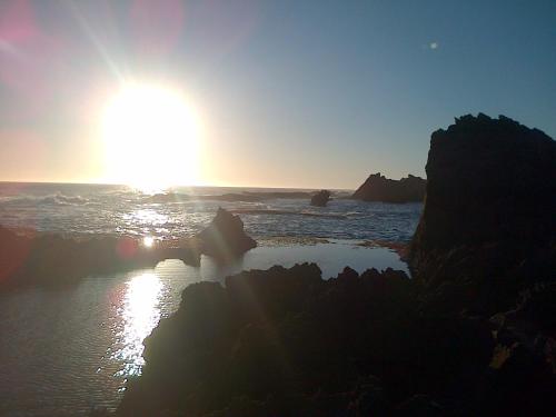 a sun setting over the ocean with rocks in the water at Shick-Shack in Eersterivierstrand