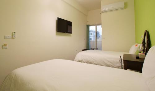 a hotel room with two beds and a flat screen tv at Trip Village-Hulk's Homestay in Taitung City