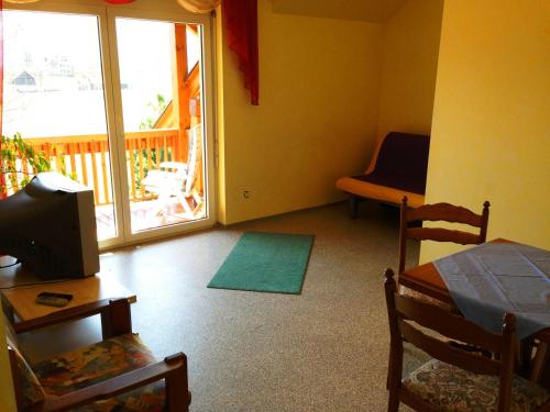 a room with a bed and a television and a balcony at Pension Haus Claudia in Drobollach am Faaker See