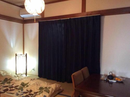 a bedroom with a table and a black curtain at Komorebi in Uji