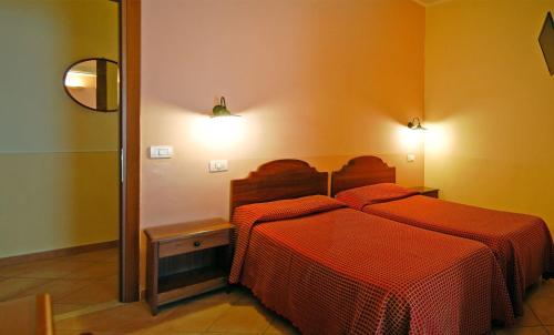 a bedroom with a bed with a red comforter at Hotel Ristorante Benigni in Campagnano di Roma