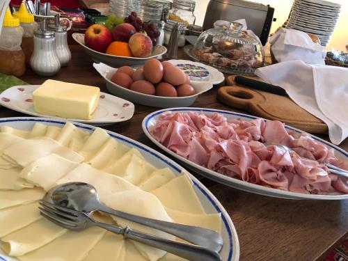 a table topped with plates of cheese and meat and eggs at Penzion V polích in Malé Číčovice